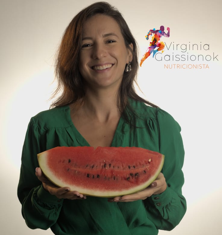 Nutricionista Virginia sorridente, segurando uma melancia em suas mãos. O fundo da imagem é claro, proporcionando um contraste suave com o foco na melancia e no sorriso da nutricionista.