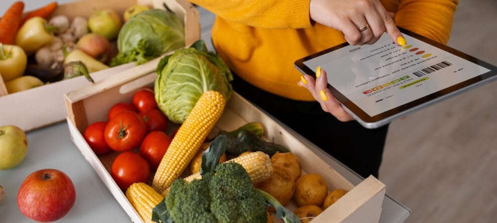 Paciente com um tablet ao seu lado, cercado por vegetais e legumes.
